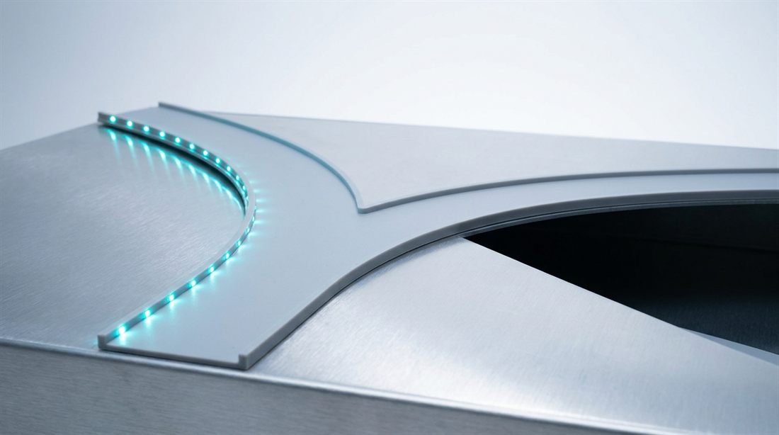 Two roads diverging across a brushed-aluminum surface — one lit with a strip of cyan lights, the other falling into shadow