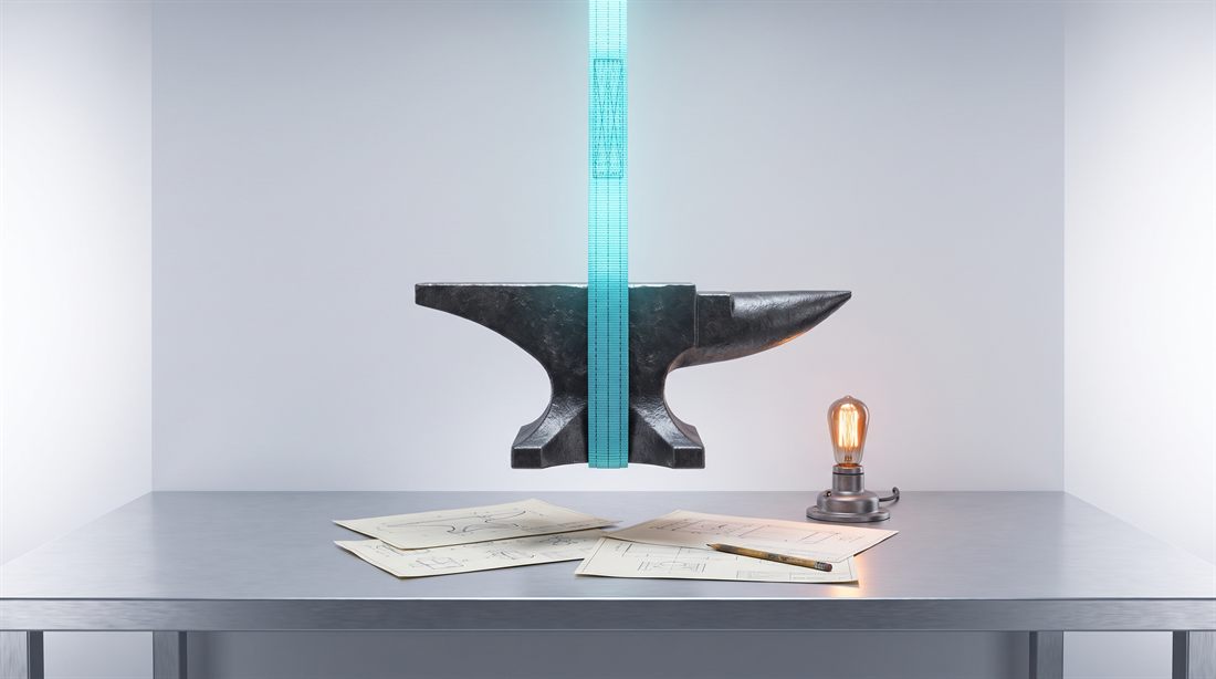 A heavy anvil lifted off a workbench by a glowing hoist strap, revealing hand-drawn sketches and a warm lamp underneath